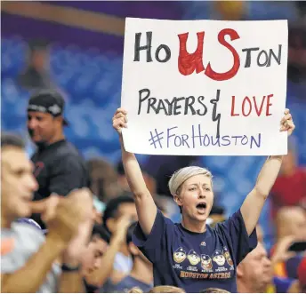  ?? Chris O’Meara / Associated Press ?? Katie Churchwell holds up a poignant reminder of why Tuesday night’s Astros-Rangers game was moved to St. Petersburg, Fla. Massive flooding in the Houston area has extended the Astros’ road trip.