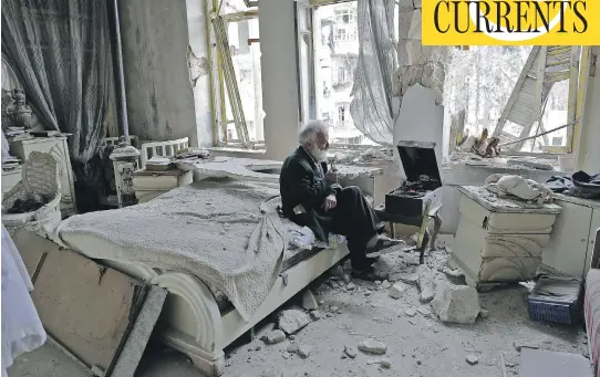  ?? PHOTOS: JOSEPH EID / AFP / GETTY IMAGES ?? Mohammad Mohiedin Anis, 70, smokes his pipe as he sits in his destroyed bedroom listening to music on his record player in Aleppo’s formerly rebel-held al-Shaar district.