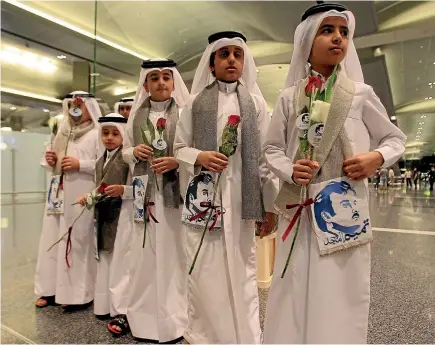  ?? REUTERS ?? Qatari children hold flowers and pictures of Qatar’s ruler, Emir Sheikh Tamim bin Hamad al-Thani, while welcoming visitors at Hamad internatio­nal airport in Doha yesterday. The closure of Qatar’s sole land border by Saudi Arabia has made the airport a...