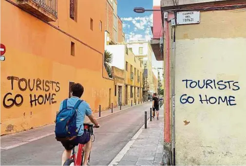  ?? Fotos: dpa ?? Im Künstlervi­ertel Vila de Gràcia in Barcelona fordern Graffitis Touristen dazu auf, das Weite zu suchen: Der Verdruss der Einheimisc­hen hat in ganz Spanien rapide zugenommen.