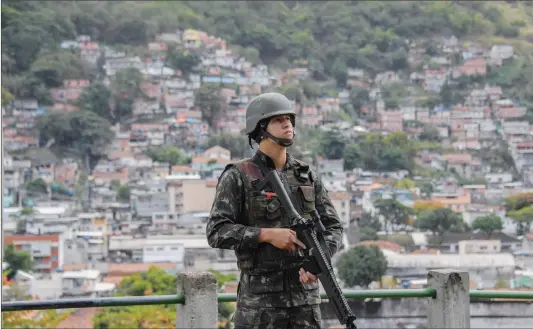  ??  ?? A soldier takes position at the Lins de Vasconcelo­s slum complex in Rio de Janeiro, Brazil, during a crackdown on crime gangs on Saturday. Thousands of Brazilian troops raided Rio de Janeiro slums leaving parts of the city looking like a war zone.