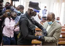  ?? — AFP file photo ?? Rusesabagi­na is handcuffed by a police officer after his pre-trial court session at the Kicukiro Primary court in Kigali.