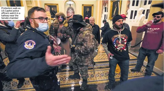  ??  ?? Protesters walk as US Capitol police officers watch in a hallway near the Senate chamber