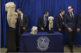  ??  ?? Investigat­ors walk around the three ancient sculptures displayed during a news conference and repatriati­on ceremony in New York.