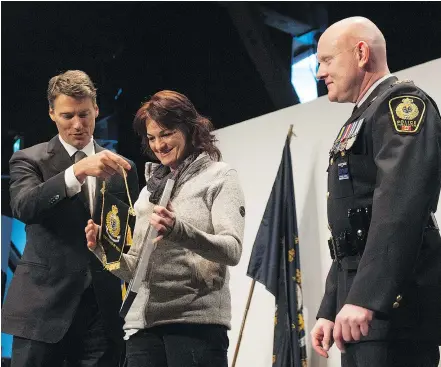  ??  ?? Penny Szekely receives an Award of Merit from Vancouver Mayor Gregor Robertson and Chief Constable Adam Palmer for helping save people from a rooming house fire in 2016. JASON PAYNE/ PNG FILES