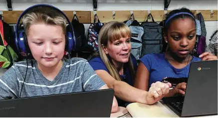  ??  ?? Dalton, center, works with students Julian Ryno, left, and Ma’Kenley Burns as they use DreamBox, which teaches math by offering problems that grow harder as users enter correct answers.