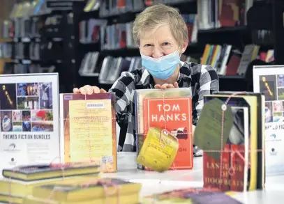  ?? PHOTO: PETER MCINTOSH ?? Turning the page on Level 3 . . . Dunedin librarian Maureen Brook prepares themed bundles of books for people seeking to drop by in Alert Level 2.