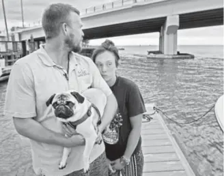  ?? Jim Damaske, Tampa Bay Times ?? Tanner Broadwell holds his dog, Remy, with Nikki Walsh on Wednesday in Madeira Beach, Fla., after their sailboat sank nearby in the Gulf of Mexico.