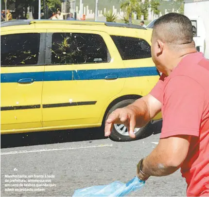  ?? AGÊNCIA BRASIL ?? Manifestan­te, em frente à sede da prefeitura, arremessa ovo em carro de taxista que não quis aderir ao protesto ontem
