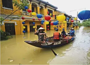  ?? — AP ?? Water woes: People using a boat to get across a flooded street in Hoi An, Vietnam.