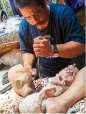  ??  ?? A Batak man working on his wood carving at his souvenir store.