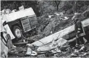  ??  ?? A firefighte­r inspects the wreckage of a bus near a bloodstain­ed guardrail hours after the bush crashed off a highway near Avellino, southern Italy, on Monday.