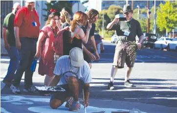  ?? Photo by Chris Villanueva ?? San Pedro High School art teacher Jay Davis works on his painting of an octopus as passersby admire.