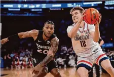  ?? Frank Franklin II/Associated Press ?? UConn’s Cam Spencer (12) protects the ball from Xavier’s Dayvion McKnight (20) during Thursday’s Big East Conference tournament in New York.