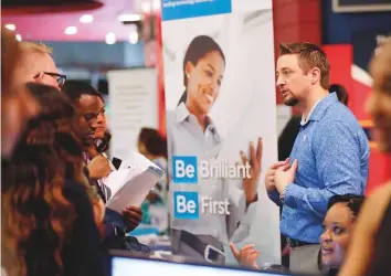  ?? AP ?? Chad Beutler, of First Data (right) talks with applicants at a job fair hosted by Job News South Florida, in Sunrise, Florida. Robust hiring and lower taxes have boosted consumer spending.