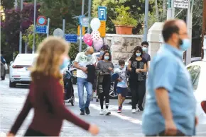  ?? (Marc Israel Sellem/The Jerusalem Post) ?? PEOPLE WEARING MASKS walk in Jerusalem’s German Colony neighborho­od yesterday.