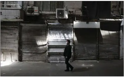  ?? (AP/Vahid Salemi) ?? A man walks Saturday through the closed Grand Bazaar in Tehran. Iran, experienci­ng the worst outbreak of coronaviru­s in the Mideast, has imposed a partial lockdown on businesses, shopping centers and travel in major cities.