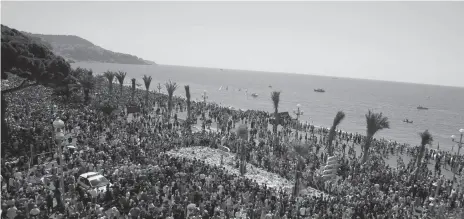  ?? AP PHOTO ?? People gather at a makeshift memorial to observe a minute of silence to honor the victims of an attack near the area where a truck mowed through revelers on the Promenade des Anglais in Nice, southern France on Monday.