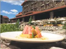  ??  ?? Omni Grove Park Inn Executive Chef Josh Thompsen prepared his heirloom tomato salad, compressed watermelon, with basil almond hummus. The background is the Grove Park Inn.