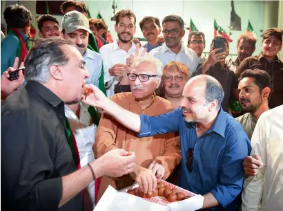  ?? — AFP ?? Activists of Imran Khan-led PTI offer sweets as the celebrate a court decision against Nawaz Sharif in Karachi.