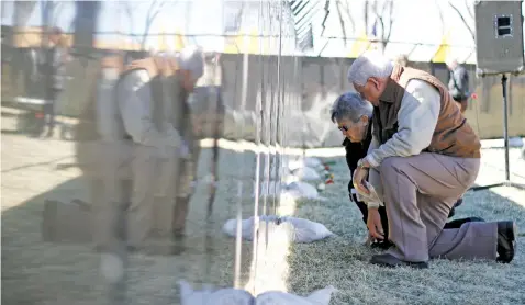  ?? LUIS SÁNCHEZ SATURNO NEW MEXICAN FILE PHOTO ?? ABOVE: Santa Feans Alfonso and Lorraine de Herrera search the Wall That Heals — a half-size replica of the Vietnam Veterans Memorial in Washington, D.C., that travels around the country — for the name of Lorraine’s brother, Vietnam veteran Pedro M. Maes, in 2014.