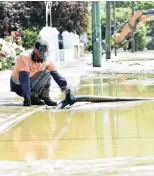  ??  ?? Dirty work . . . Russell Davies, of Alexandra, clears a drain in Scotland St, Roxburgh’s main street.