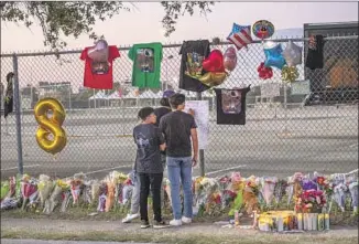  ?? Thomas Shea AFP/Getty Images ?? TRAVIS SCOTT performs in November at the Houston festival Astroworld, top. Ten people died. Teens visit a makeshift memorial, bottom. A spokespers­on for Live Nation, which faces more than 300 lawsuits in the tragedy, disputes that the concert giant cut corners on safety and security.