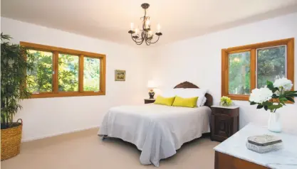  ?? Kurt Lai ?? Wood-framed windows overlook the neighborho­od in this carpeted bedroom.