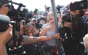  ?? AP ?? An anti-migrant demonstrat­or is surrounded by the press as she argues with a woman during a protest against the presence of thousands of Central American migrants in Tijuana, Mexico.