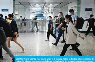  ??  ?? BEIJING: People wearing face masks walk in a subway station in Beijing. China is looking to reduce its reliance on overseas markets and technology for its economic developmen­t, government advisers said yesterday. —AFP