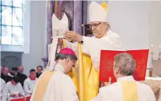  ?? FOTO: MARKUS ULMER ?? Bischof Gebhard Fürst weiht Matthäus Karrer zum Weihbischo­f der Diözese Rottenburg-Stuttgart und setzt ihm die Mitra auf.