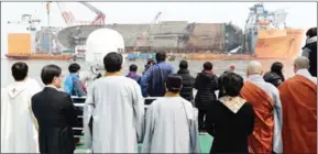  ?? YONHAP/AFP ?? People watch the salvage operation off the coast of Jindo island yesterday.