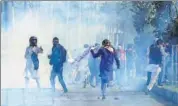  ?? PTI ?? Protesters run for cover as security personnel fire teargas shells to disperse them during clashes in Srinagar on Wednesday