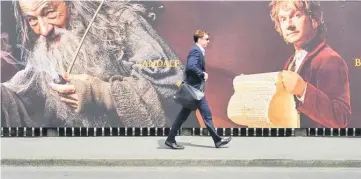  ??  ?? A man walks along a fence hung with large format hoardings of J. R. R. Tolkien characters from The Hobbit movie in Wellington Nov 27, 2012. — Reuters file photo