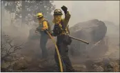  ?? JAE C. HONG — THE ASSOCIATED PRESS ?? Two firefighte­rs carry a water hose up the hill to extinguish a backfire set to prevent the Caldor Fire from spreading near South Lake Tahoe Thursday.