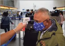  ?? Jae C. Hong / Associated Press ?? A traveler gets his temperatur­e checked while waiting in line to check in at the Los Angeles Internatio­nal Airport on Monday.