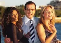  ??  ?? This file photograph taken on October 5, 1999 shows British actor Roger Moore (center) posing with actresses Traci Bingham (left) and Eva Halina in Cannes.