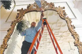  ??  ?? Mark Heldt places lights on a large mirror in the State Dining room.