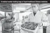  ??  ?? A medical worker holding bags of liquid traditiona­l Chinese medicine.