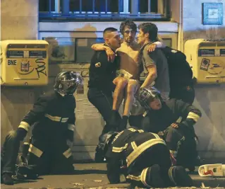  ?? (Christian Hartmann/Reuters) ?? MEMBERS OF the French fire brigade help a man wounded near the Bataclan concert hall during the fatal shootings in Paris on November 13, 2015.