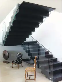  ??  ?? Christophe­r Bradshaw’s cool black staircase looks like a painting by Dutch artist Escher. Built of maple plywood, it has no posts. The support is a steel structure hidden inside a hollow box that creates the staircase, which has the same profile underneath as above.