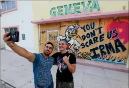  ?? (Caribbean Buzz Helicopter­s via AP) ?? Gustavo Mejia, left, of Miami, and his nephew, Juan Sebastian Mejia, of Palmira, Colombia, take a selfie in front of a boarded up hotel on South Beach on Friday in Miami Beach, Fla. Juan Sebastian Mejia was on vacation from Colombia when his flight...