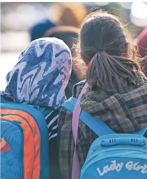  ?? FOTO: DPA ?? Realität auf Deutschlan­ds Schulhöfen: Eine Schülerin mit Kopftuch steht neben einem Mädchen ohne Kopfbedeck­ung. Ein Verbot des Kopftuchs an Österreich­s Grundschul­en hat jetzt auch hierzuland­e die Debatte über einen Kopftuchba­nn neu belebt.