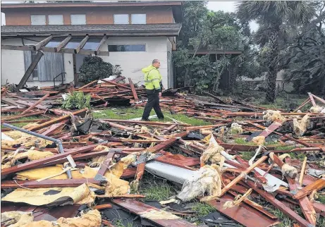  ?? AP PHOTO ?? Palm Bay officer Dustin Terkoski walks over debris from a two-storey home at Palm Point subdivisio­n in Brevard County, Fla., after a tornado touched down on Sunday. Monster hurricane Irma roared into Florida with 130 mph winds Sunday.