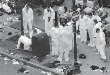  ?? DARREN MCCOLLESTE­R/GETTY IMAGES ?? Investigat­ors in white jumpsuits work the crime scene on Boylston Street following Monday’s bomb attack at the Boston Marathon. ‘This stuff is more like Baghdad and Bombay than Boston,’ said Bruce Mendelsohn, who tended to victims.