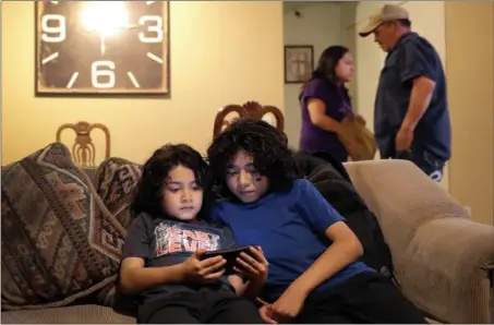  ?? MATT YORK — THE ASSOCIATED PRESS ?? Joseph Diaz, 10, right, and his brother, John Diaz, 7, watch videos as their parents, Karina Ruiz and Humberto Diaz prepare dinner at their home, Thursday in Glendale, Ariz. Karina is in a program dating back to the Obama administra­tion that allows immigrants brought here as children to work and protects them from deportatio­n.