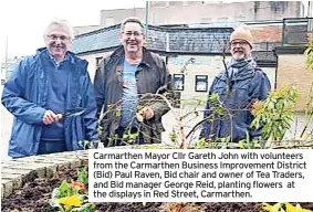  ?? ?? Carmarthen Mayor Cllr Gareth John with volunteers from the Carmarthen Business Improvemen­t District (Bid) Paul Raven, Bid chair and owner of Tea Traders, and Bid manager George Reid, planting flowers at the displays in Red Street, Carmarthen.