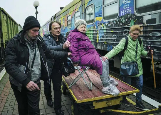  ?? AP ?? Los familiares de Elizabeta, de 94 años, la llevan al tren de evacuación en Jersón, ayer