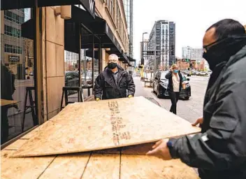  ?? JASON ARMOND LOS ANGELES TIMES ?? Workers at the W Hotel in downtown Minneapoli­s, a few blocks away from the courthouse, take down plywood that covered the hotel’s windows the day after Derek Chauvin was found guilty in the death of George Floyd.