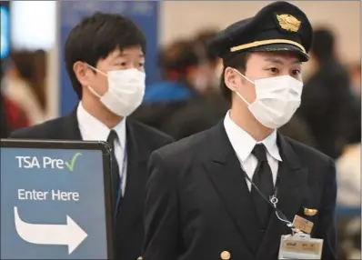  ?? (AFP) ?? (File photo) Airline pilots wearing face mask arrive at TSA PreCheck for an outbound flight at Los Angeles Internatio­nal Airport.